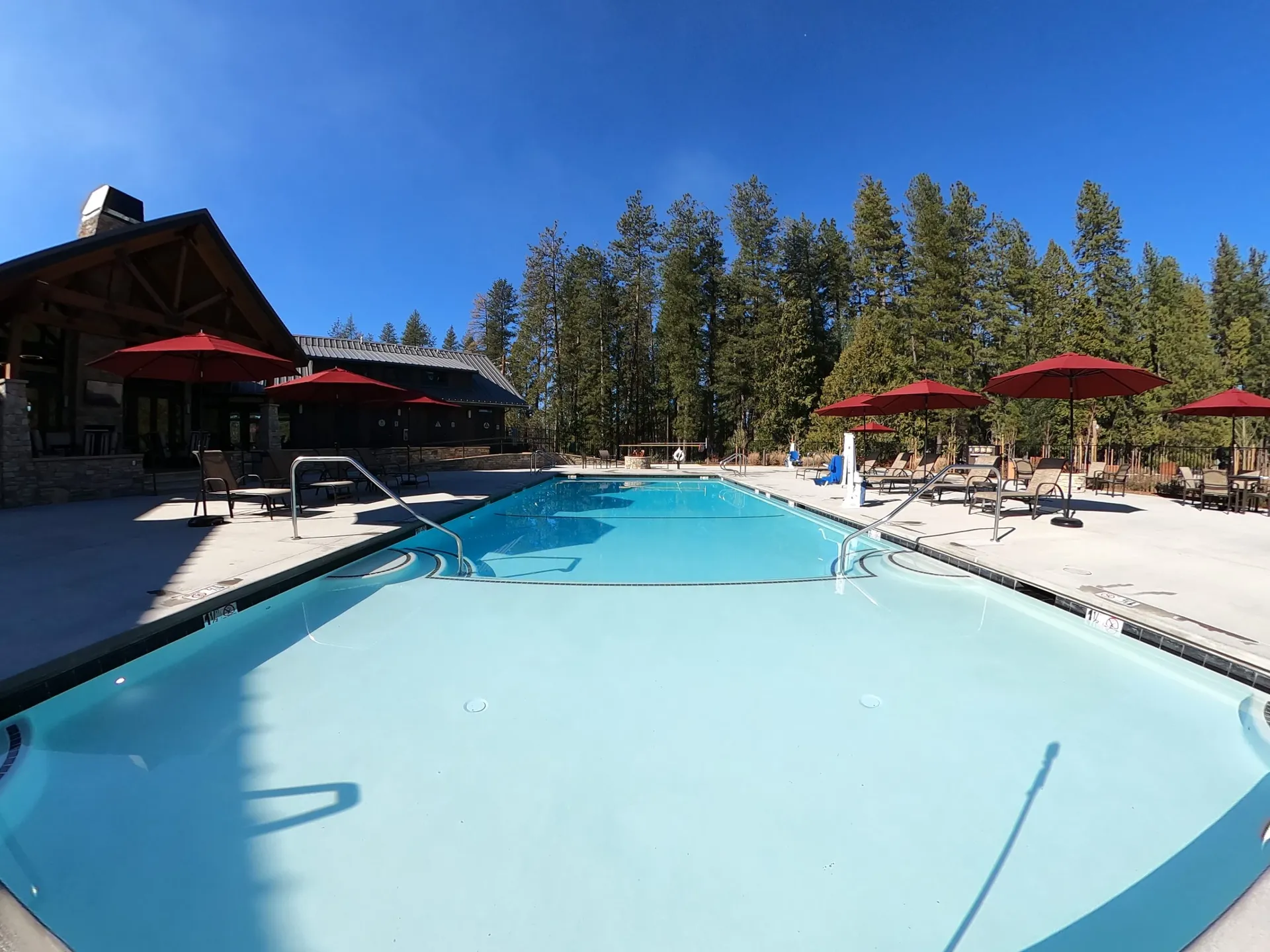 Heated pool beside the lodge with umbrellas at Grass Valley RV Resort